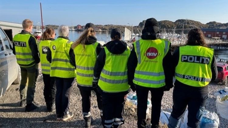 personer med ryggen til og gule vester med logo fra a-krimsamarbeidet 