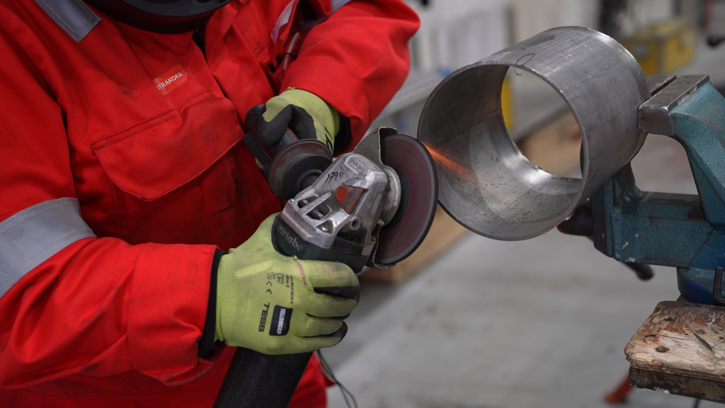 To hender som holder en maskin og sveiser på et rør 